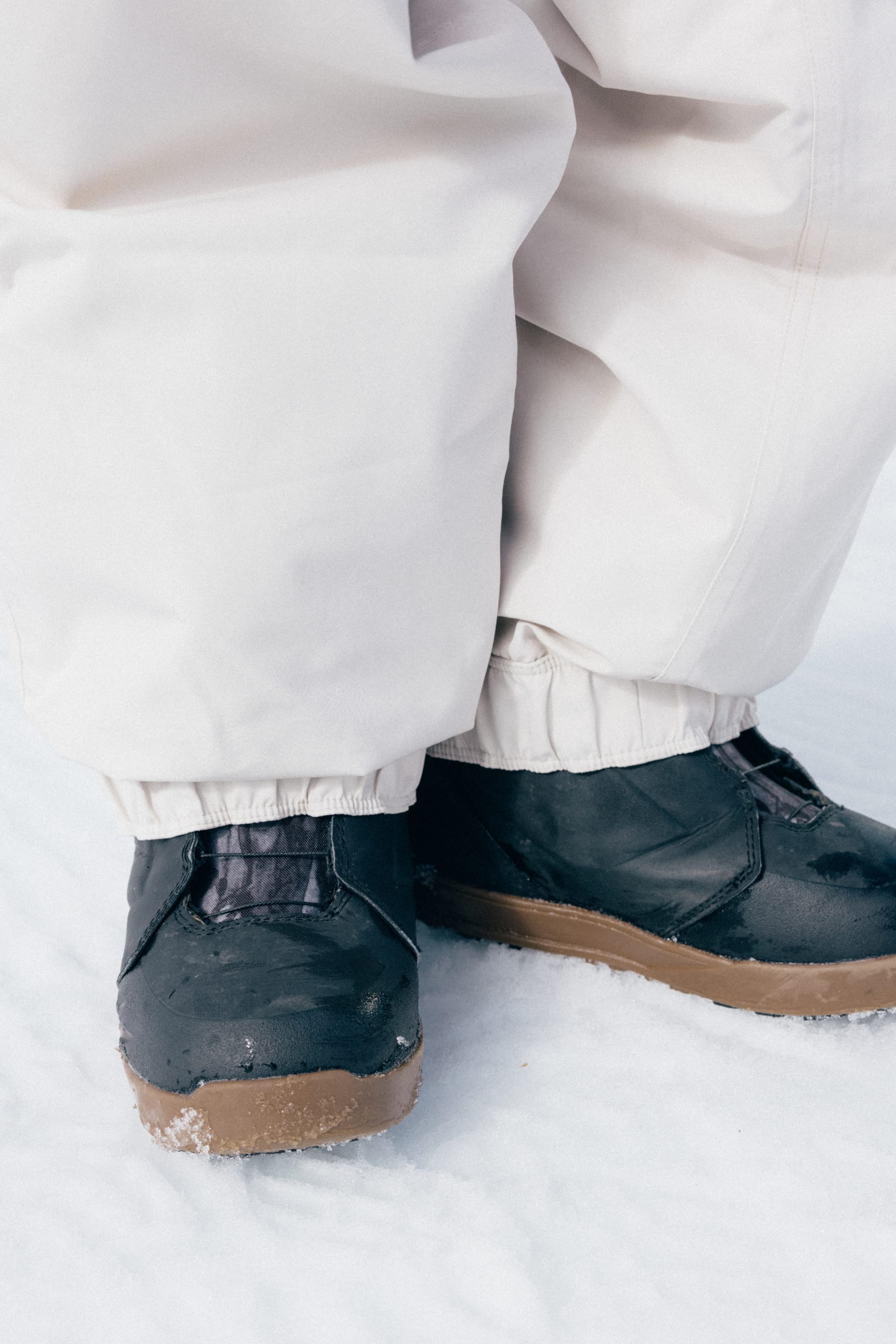 A person wearing 686 Women’s Outline™ Shell Pant and black winter boots is standing on snow.