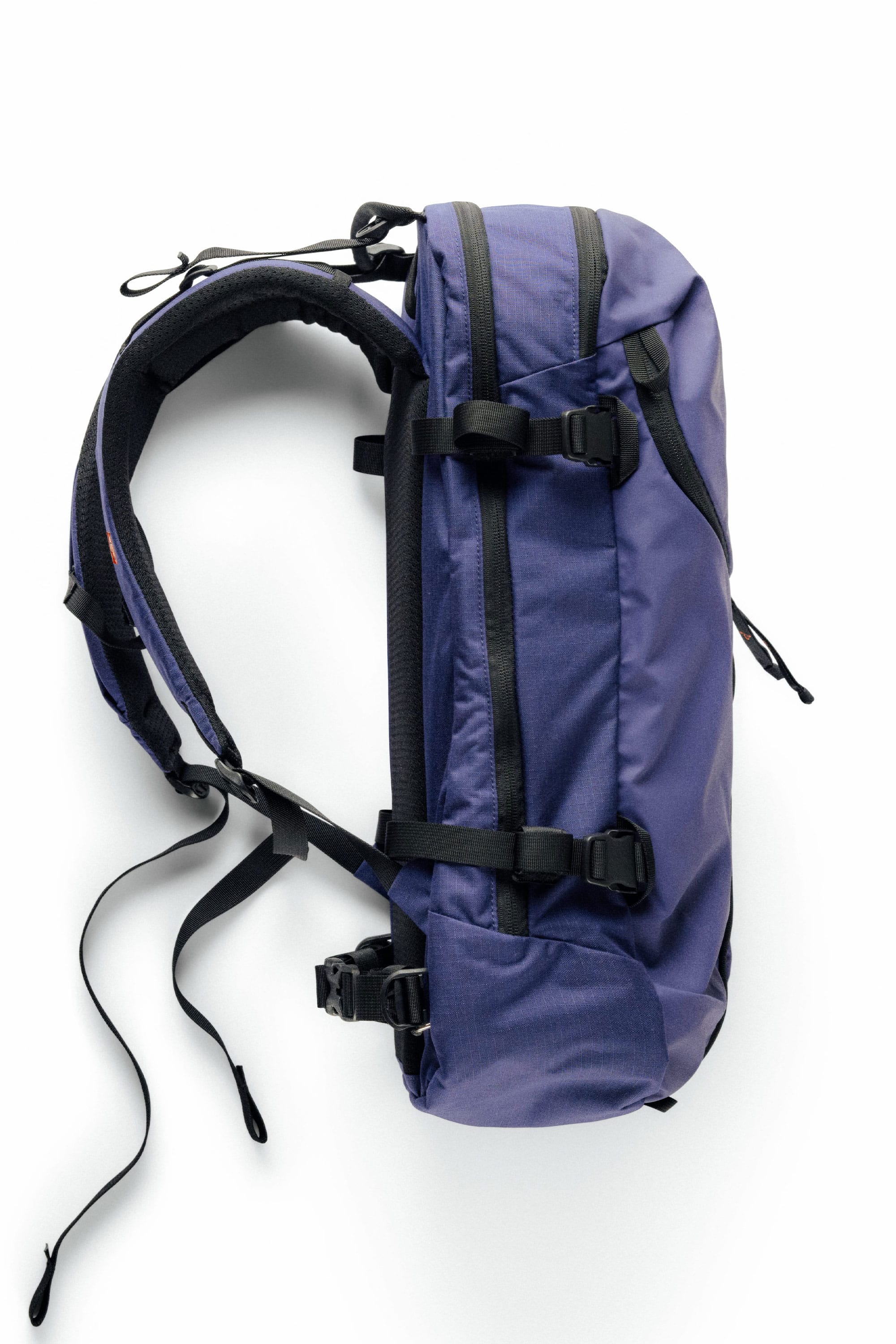 The 686 Mystery Ranch x 686 Qi 22L Snow Pack is a blue and black backpack featuring padded shoulder straps, adjustable buckles, and a streamlined design, shown against a white background.