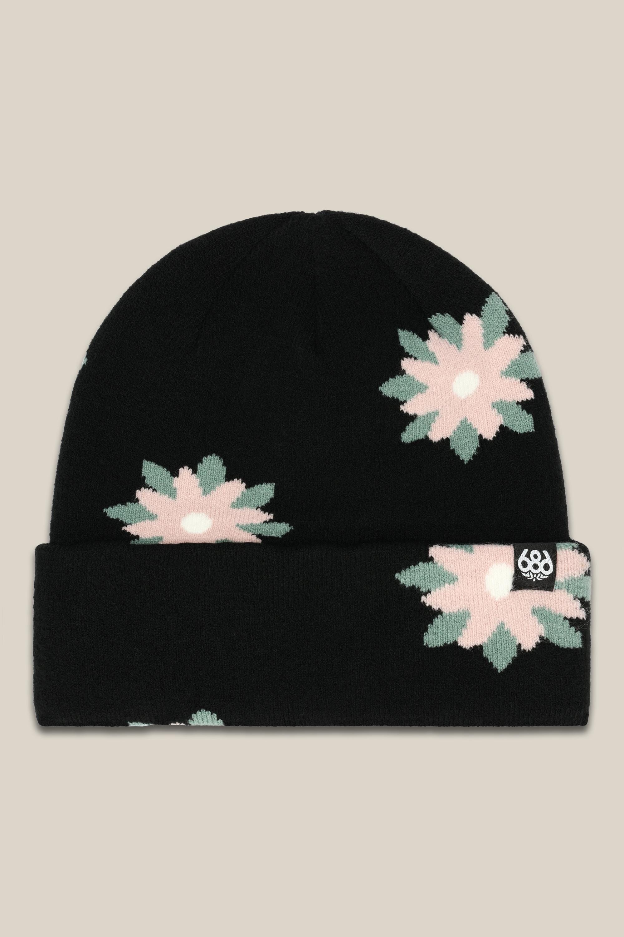 The 686 Womens Dazey Beanie is a black acrylic knit hat with a folded brim, vibrant pink, green, and white geometric flower pattern, and a small logo tag on the cuff.