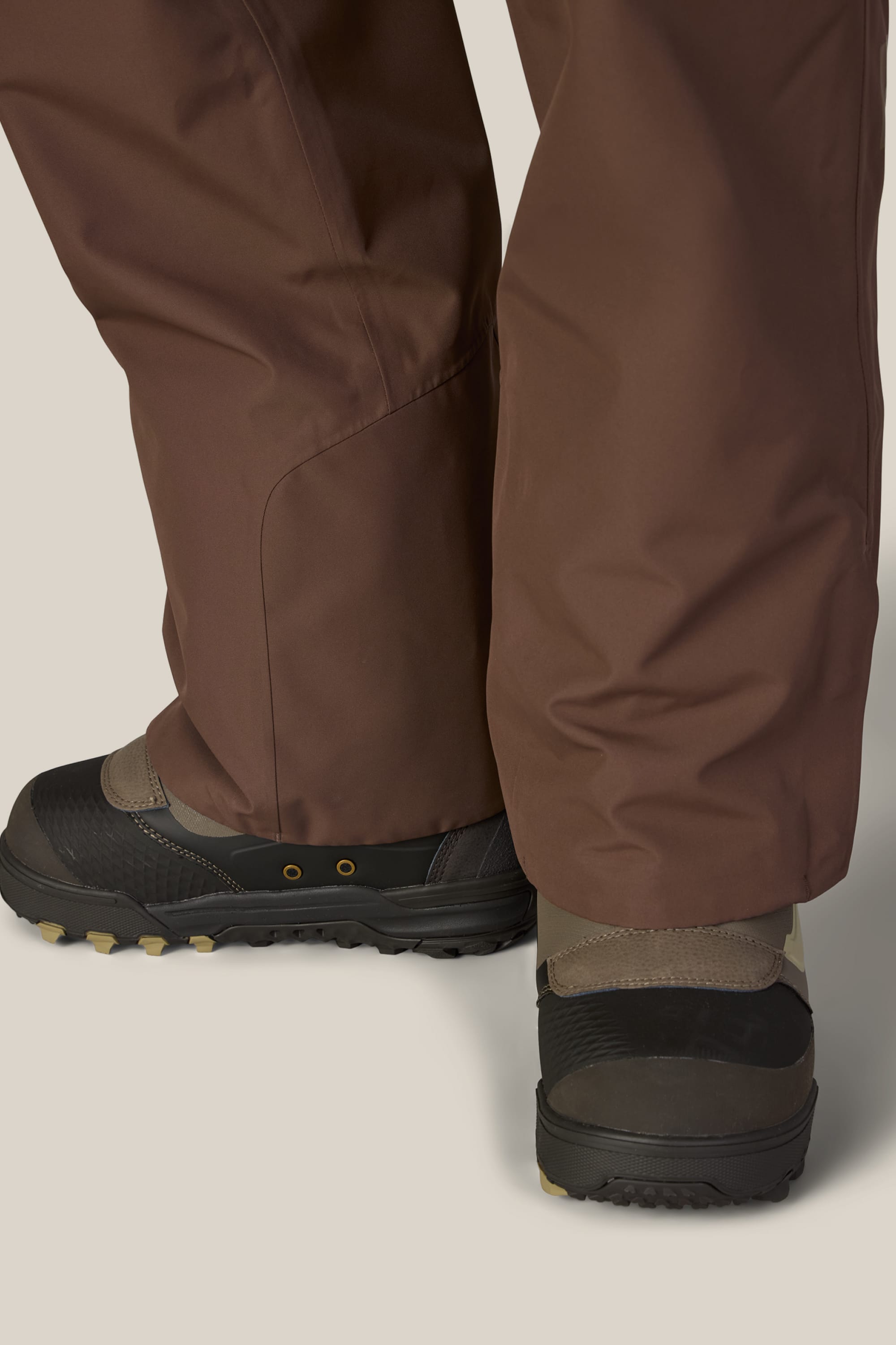 A close-up of a person wearing the 686 Women’s Geode Thermagraph® Pant and black hiking boots with rugged soles, standing on a light-colored surface.