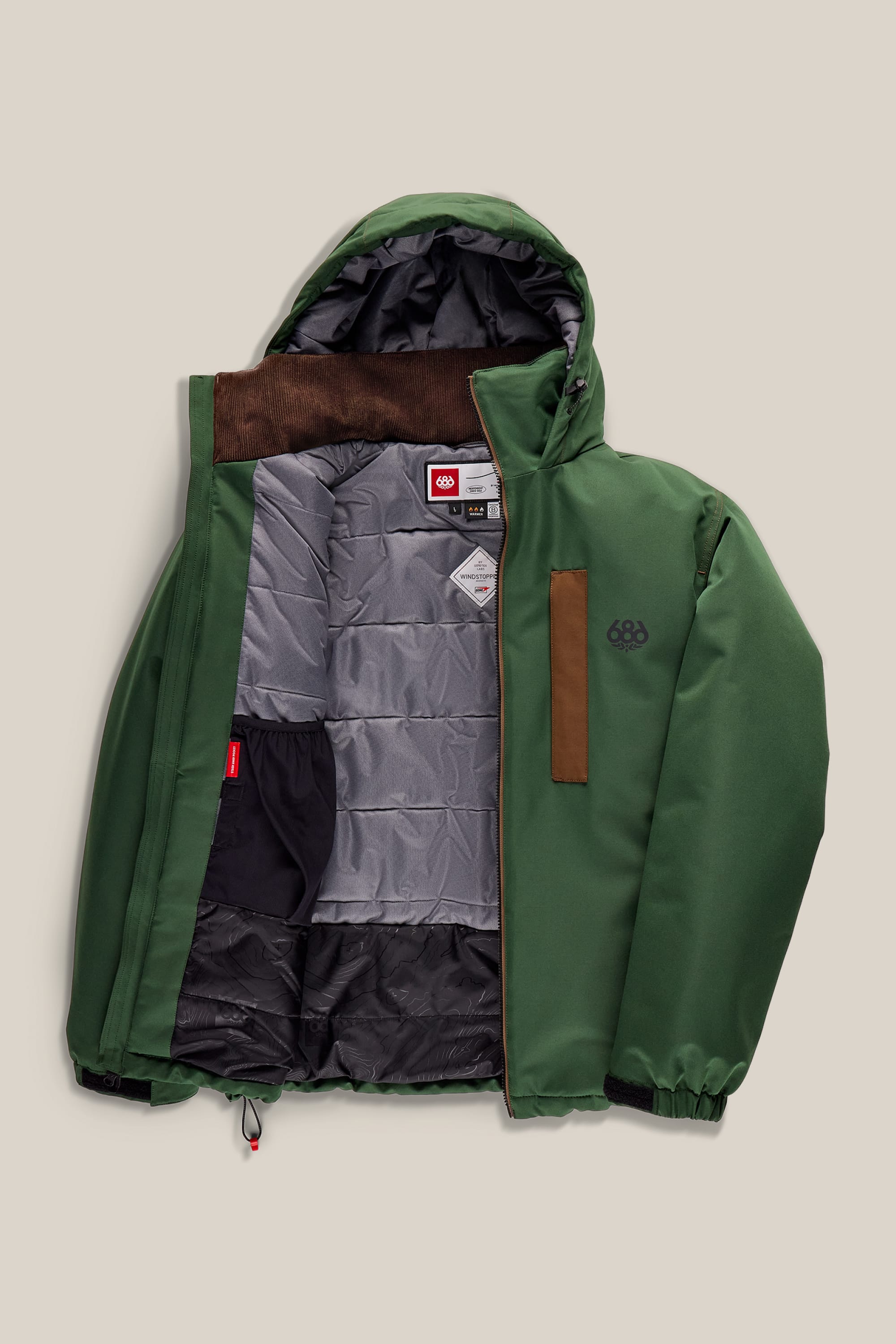 The 686 Men’s WINDSTOPPER® Guideline Insulated Jacket by GORE-TEX® LABS is displayed unzipped, showcasing its gray quilted lining, interior pockets, and a brown chest accent. The green jacket is laid flat on a neutral background.