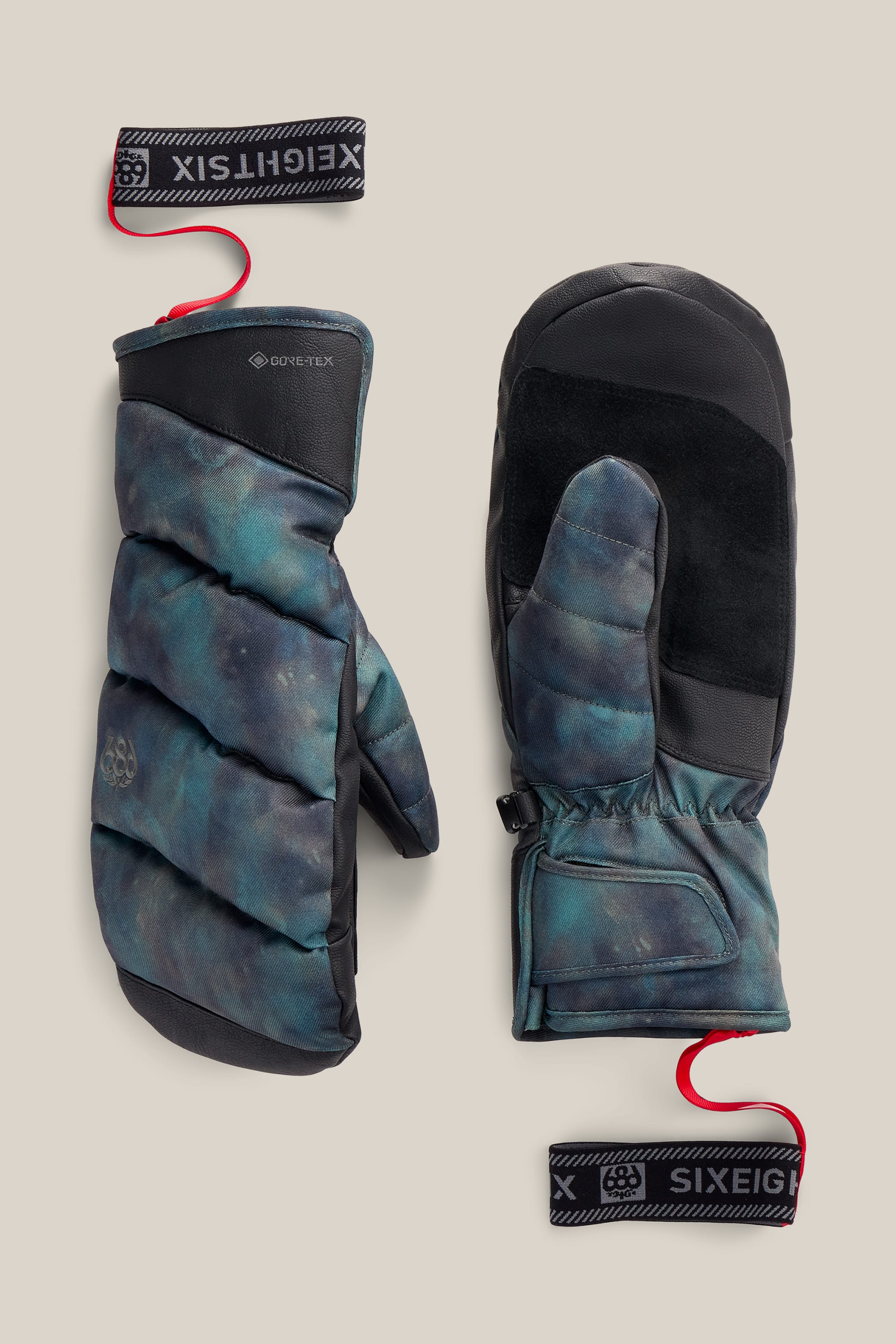 Pair of blue-green Men’s GORE-TEX® Buffer Insulated Mitts by 686, featuring black accents, black palms, and red wrist leashes attached to black-and-white labels displaying the 686 logo. These insulated PU winter mittens are shown from both the top and palm sides.
