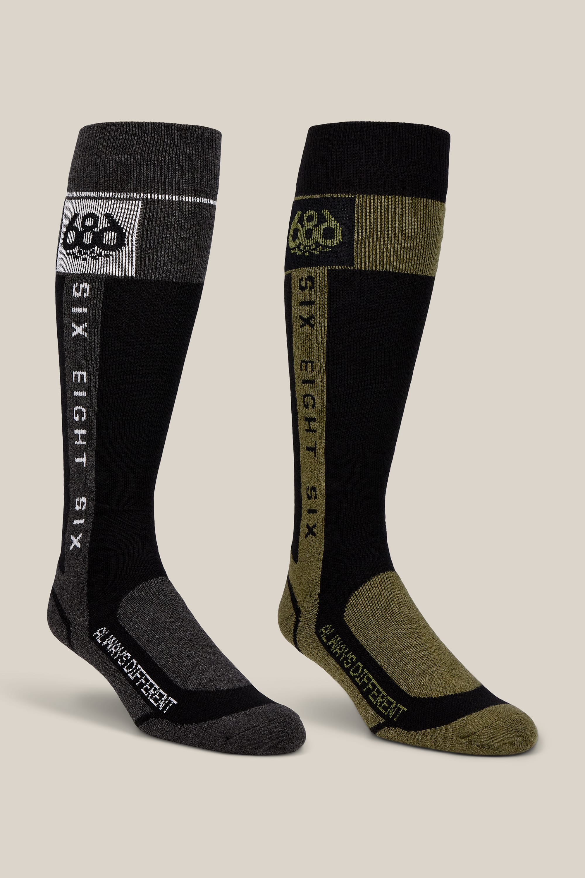 Experience comfort and style with the 686 Men’s Merino Flow Sock 2-Pack. This set includes two knee-high performance socks—one in black and gray, the other in black and olive green—each featuring bold SIX EIGHT SIX and A WHOLE DIFFERENT text printed down the side. Crafted by 686 with quality materials for long-lasting wear, these acrylic men’s socks deliver enduring comfort with every step.