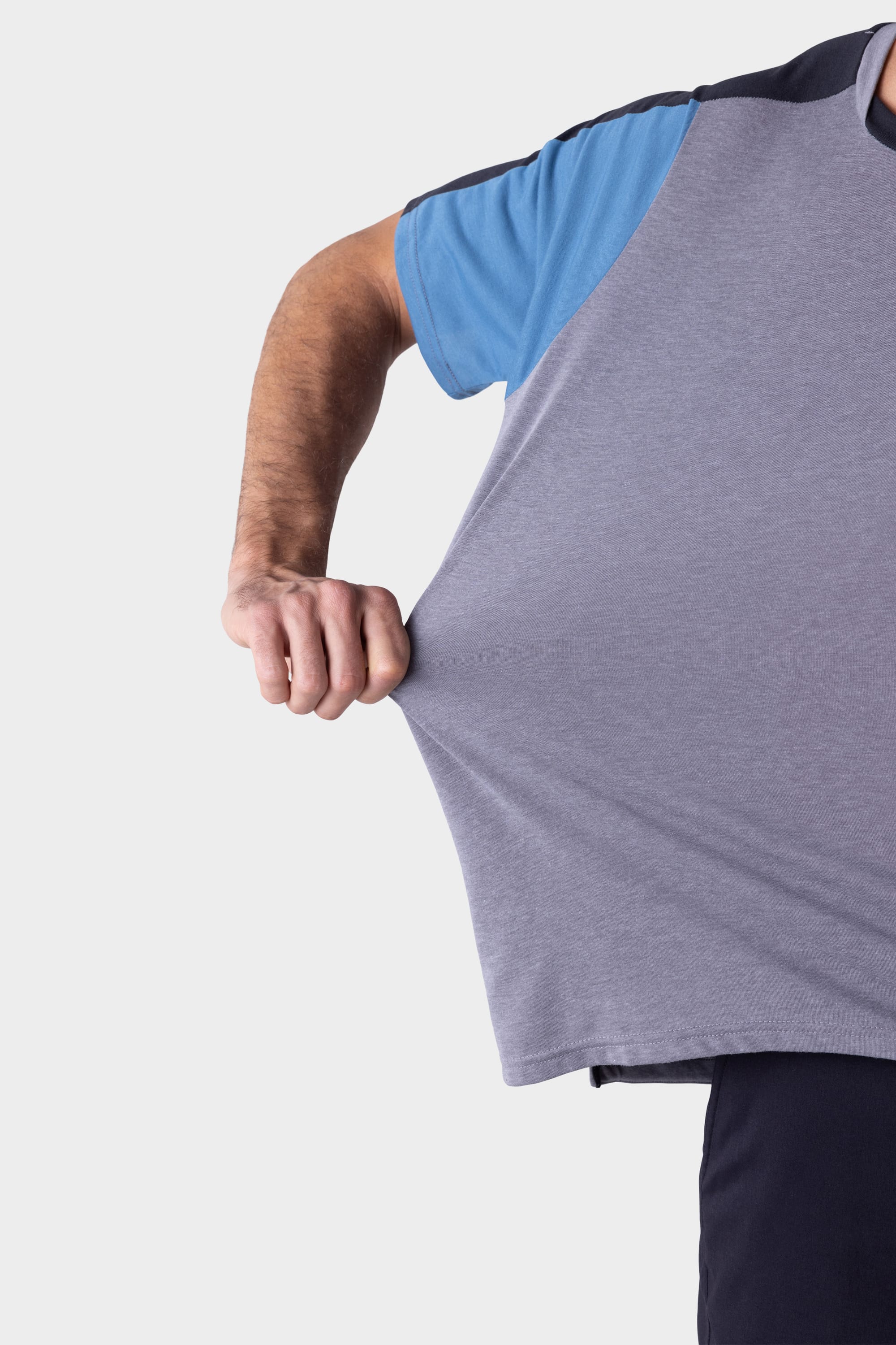 A person wearing the 686 Mens Rival Short Sleeve Bike Jersey stretches the blue and grey shirt outward with their right hand against a white background.