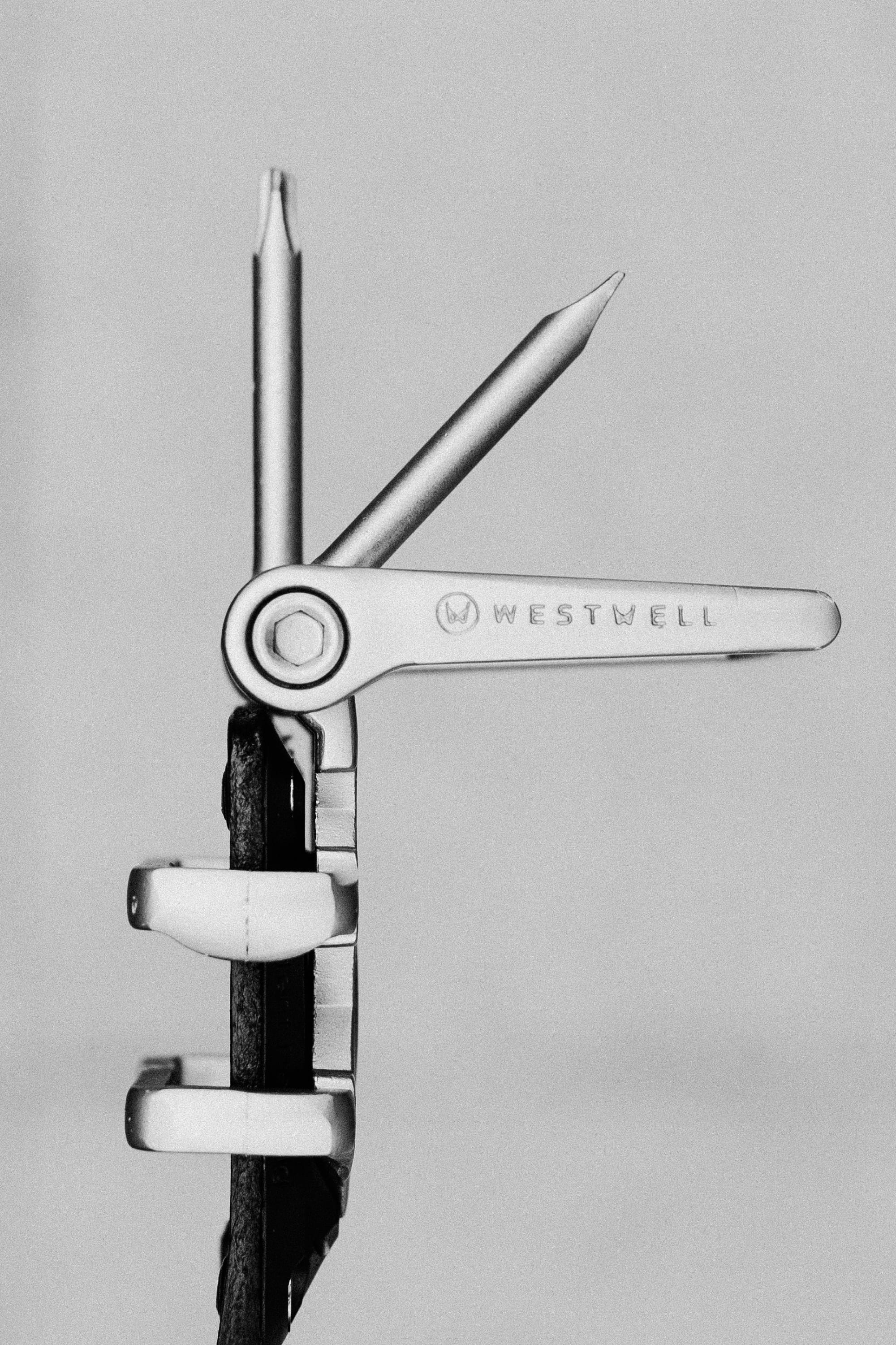 A black and white photo of the 686 Westwell Voyager Belt by Westwell, showcasing two extended tools—one resembling a screwdriver, the other a file—set against a plain background.