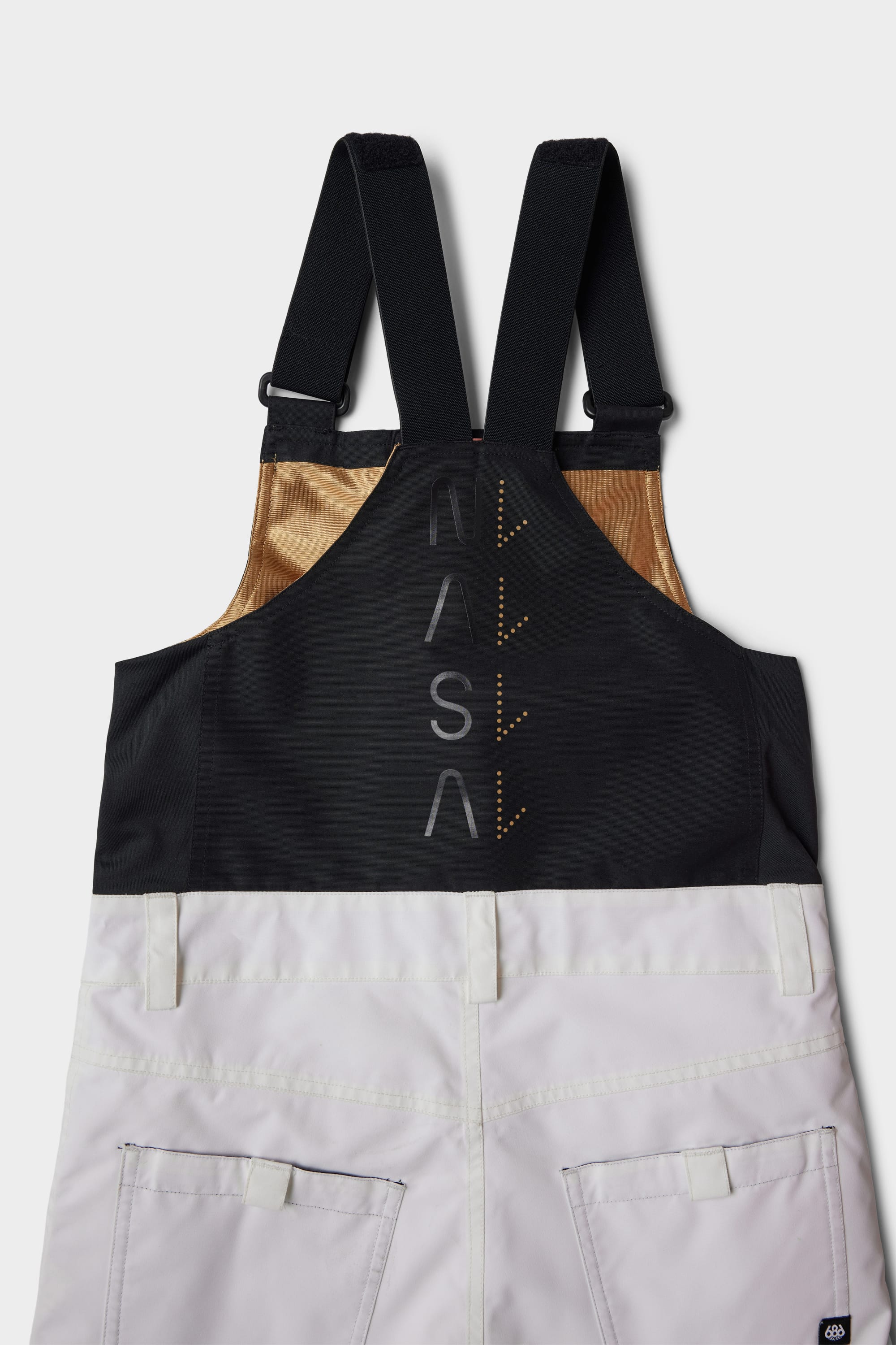 The 686 Youth Exploration Insulated Bib by 686 features color-blocked overalls with black straps and top, beige sides, white lower section, embroidered NASA text with orange downward arrows on the back, and two visible pockets.