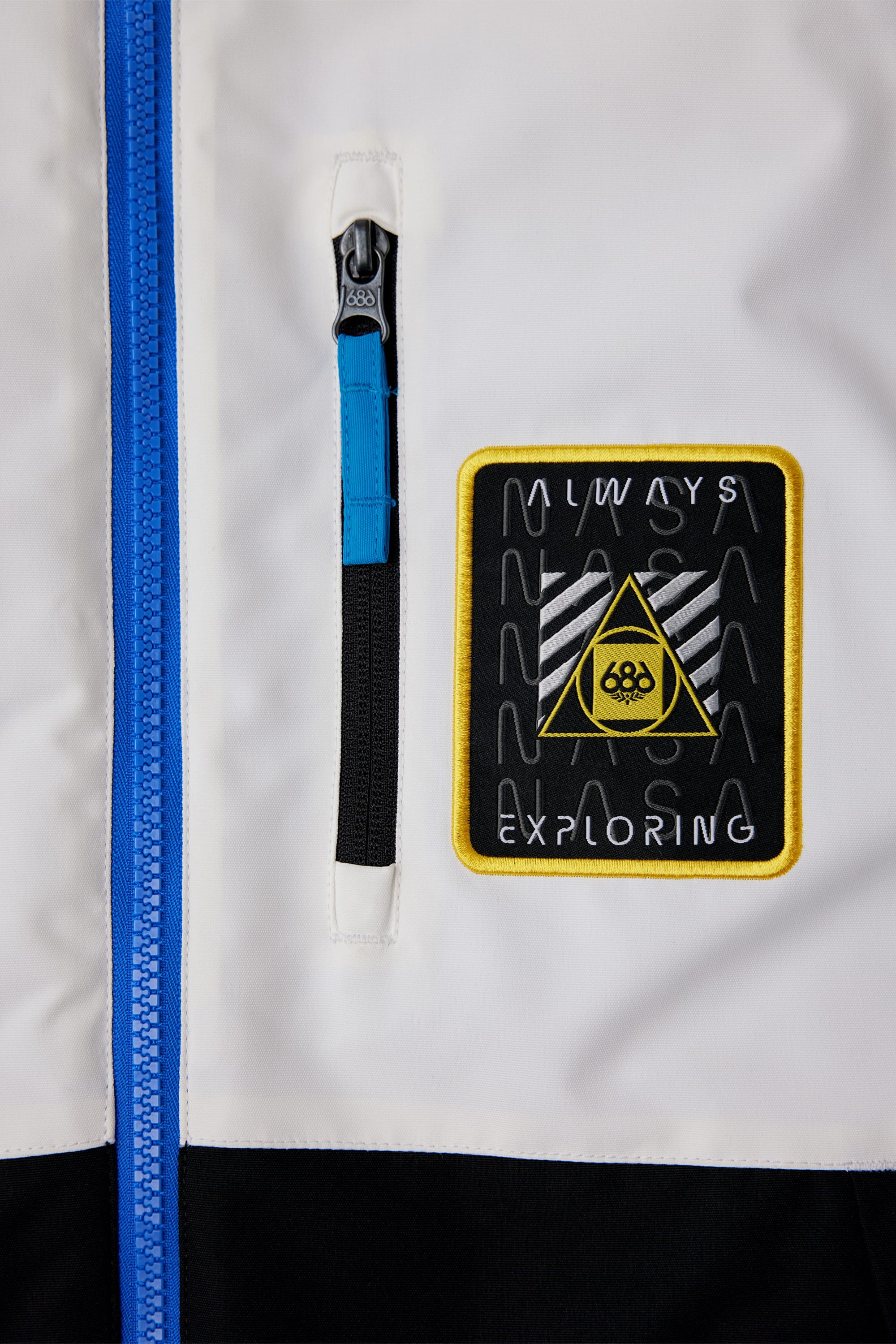 Close-up of the 686 Youth Exploration Insulated Jacket by 686 in white, with a blue zipper, small vertical zip pocket, and a patch reading NASA in wavy letters above ALWAYS EXPLORING on black with a yellow triangle.