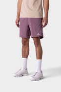 A person wearing 686 Mens ATP Stretch Performance Short in mauve, a beige shirt, white crew socks, and white sneakers stands against a plain light gray background; the face is not visible.