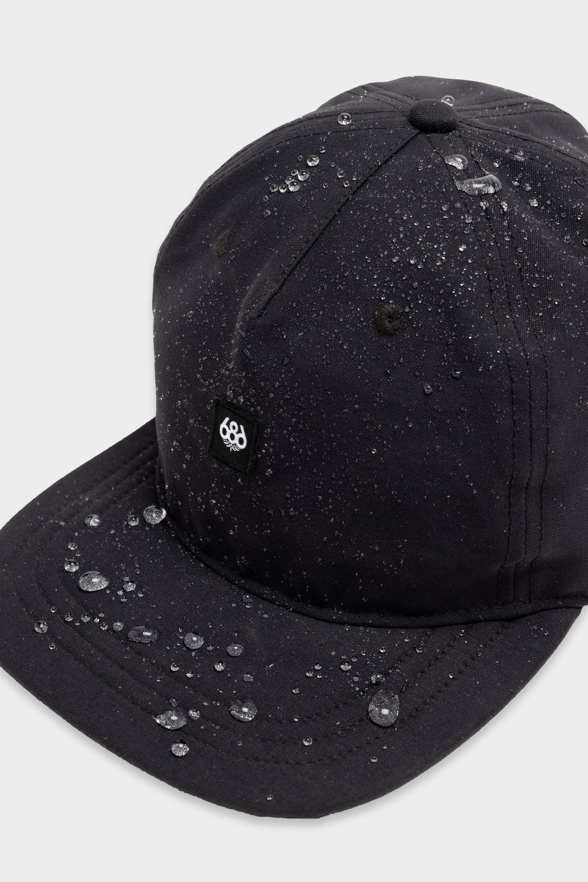 The 686 Packable Everywhere Hat by 686 is a black cap with water-resistant fabric that repels droplets. It features a small black patch with the white 686 logo on the front panel.