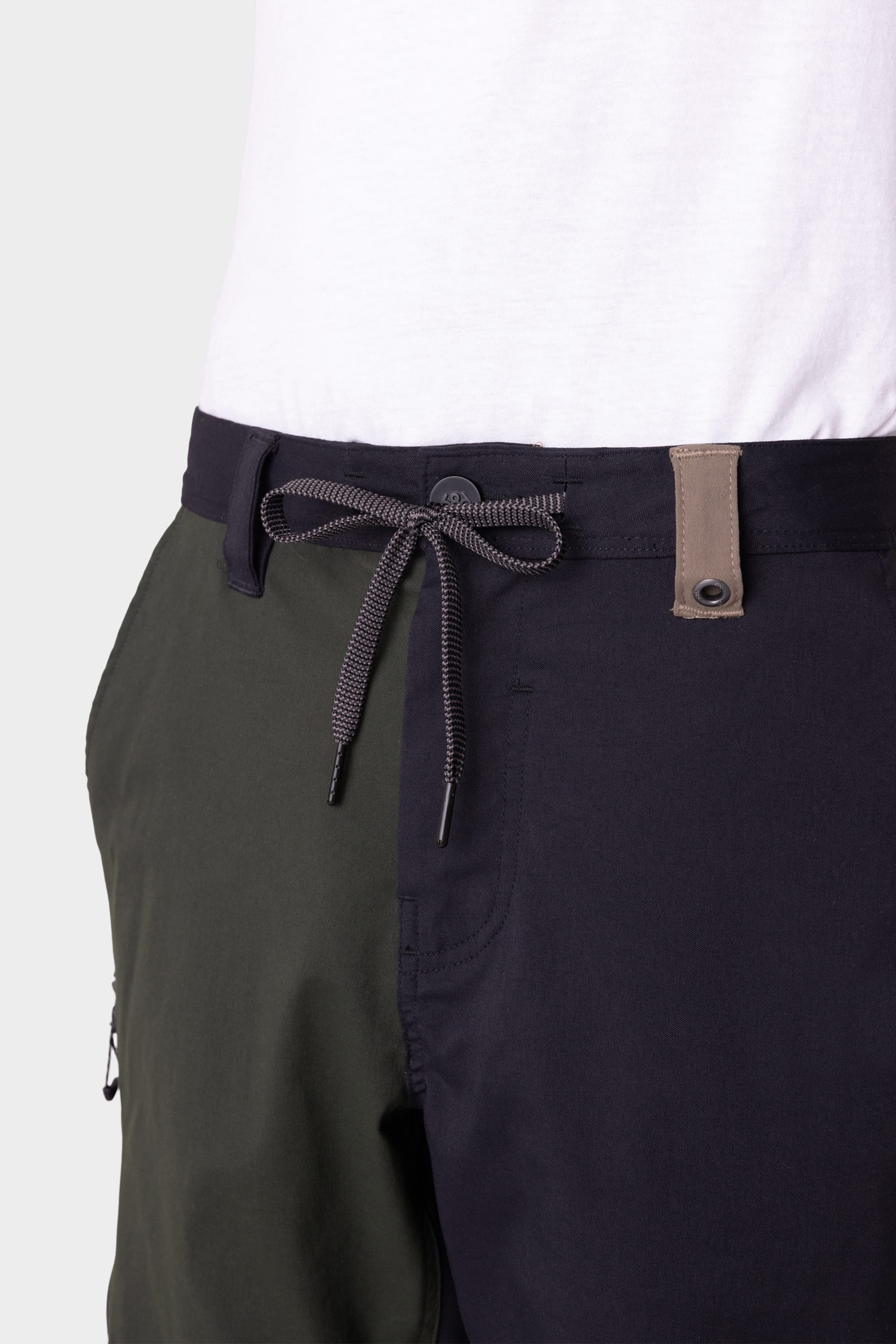 Close-up of a person wearing 686 Mens Anything Hybrid Cargo Short by 686, featuring a minimalist two-tone design with olive green and dark navy legs, gray drawstring, and a partially visible white T-shirt.
