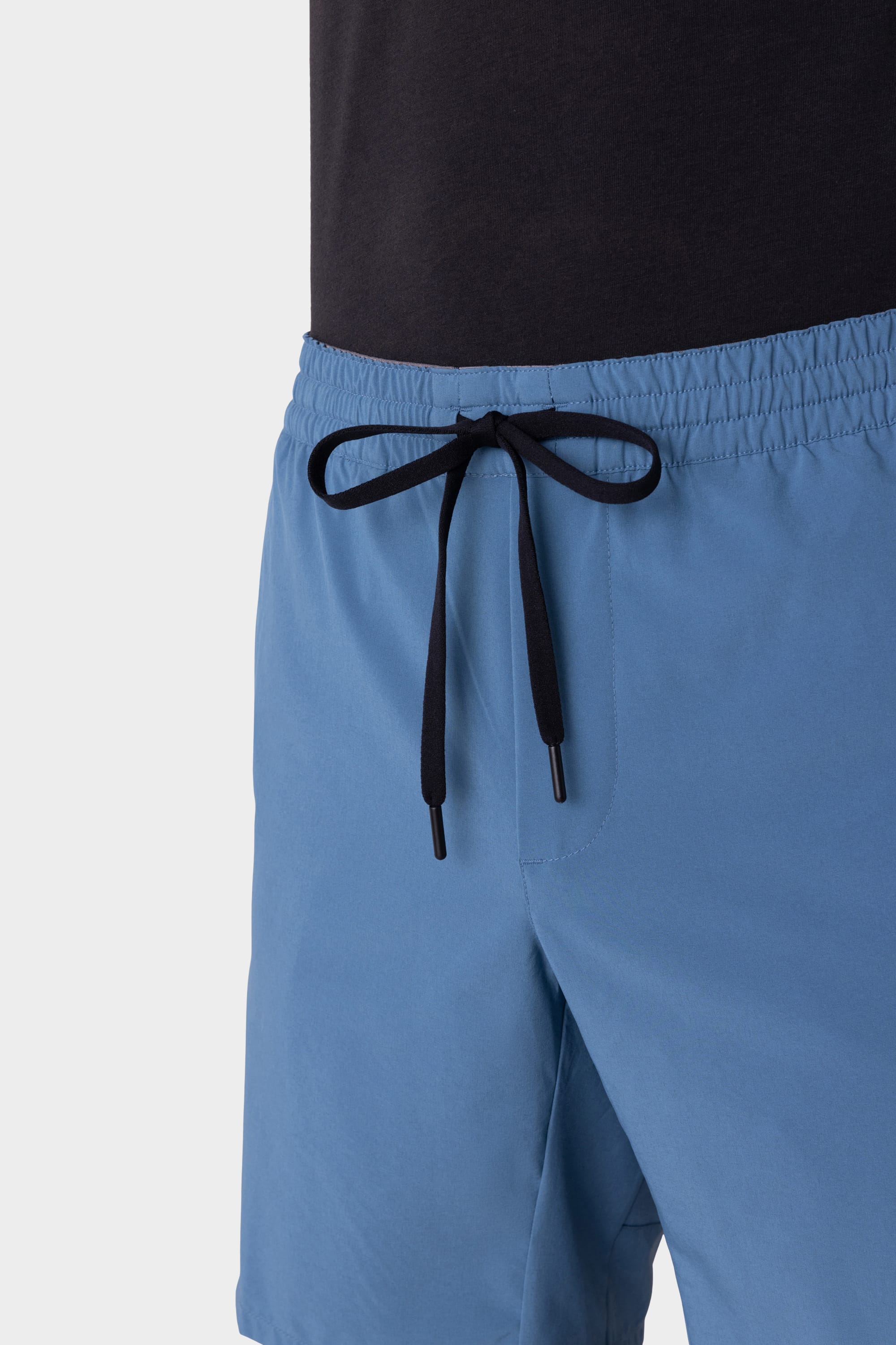 A man models the 686 Mens ATP Stretch Performance Short in light blue with a black waistband tie, paired with a black shirt, shown waist to mid-thigh against a plain light background. Brand: 686.