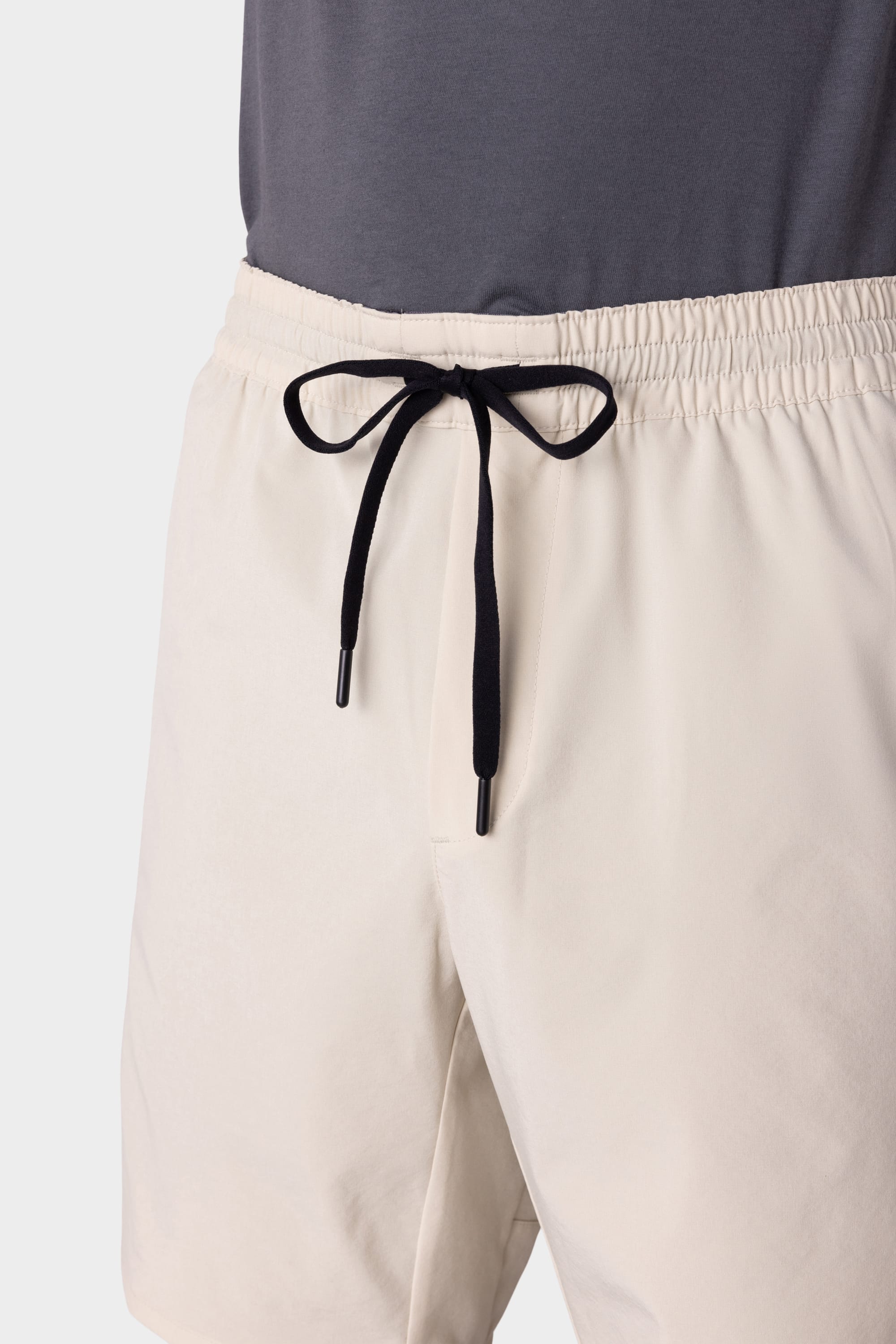 A person wearing 686 Mens ATP Stretch Performance Shorts in light beige with a black drawstring, paired with a dark grey shirt, shown from waist to mid-thigh against a plain background. Brand: 686.