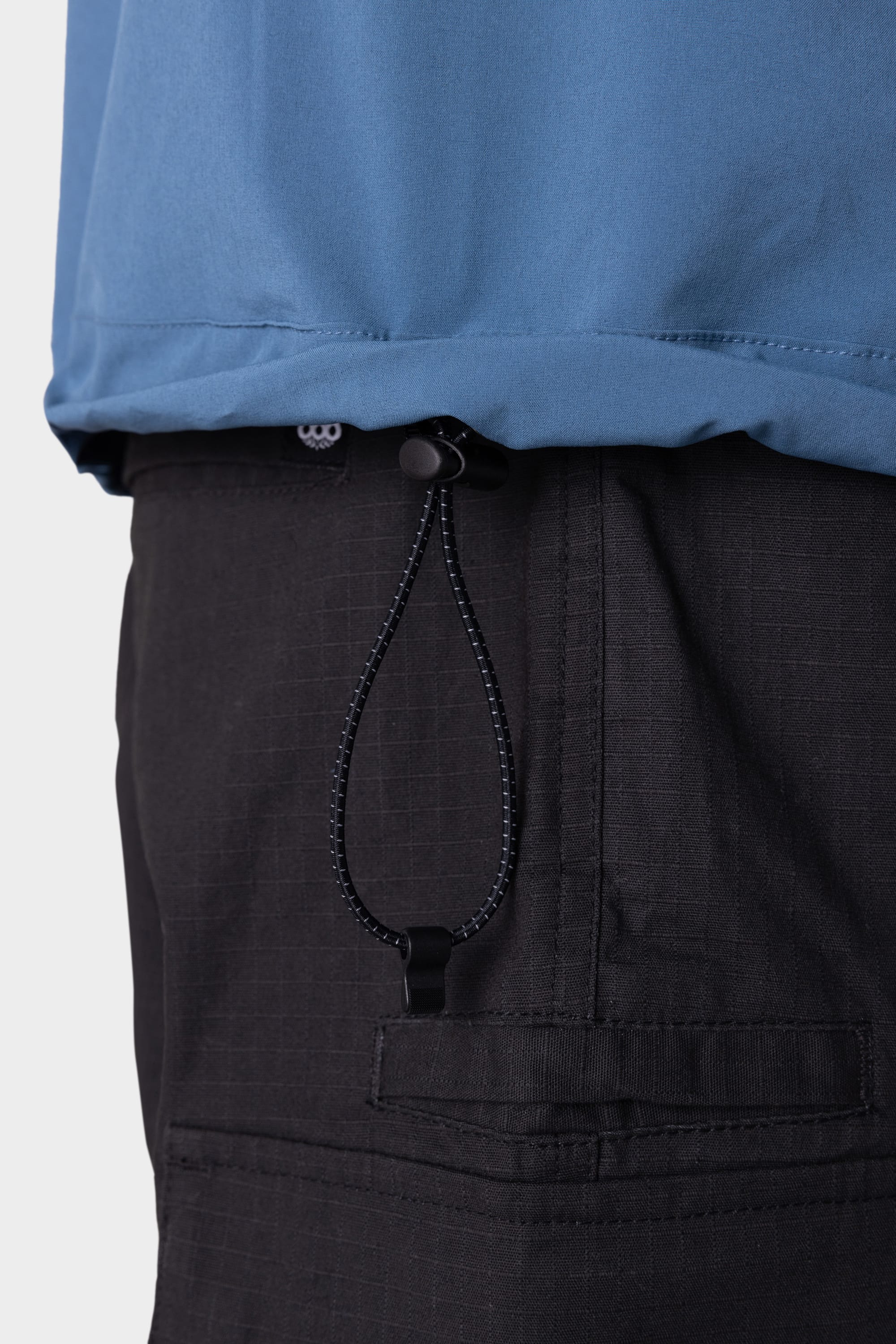 A close-up of a person wearing the 686 Mens ATP Stretch Wind Jacket, highlighting the adjustable black elastic cord and toggle detail at the hem.