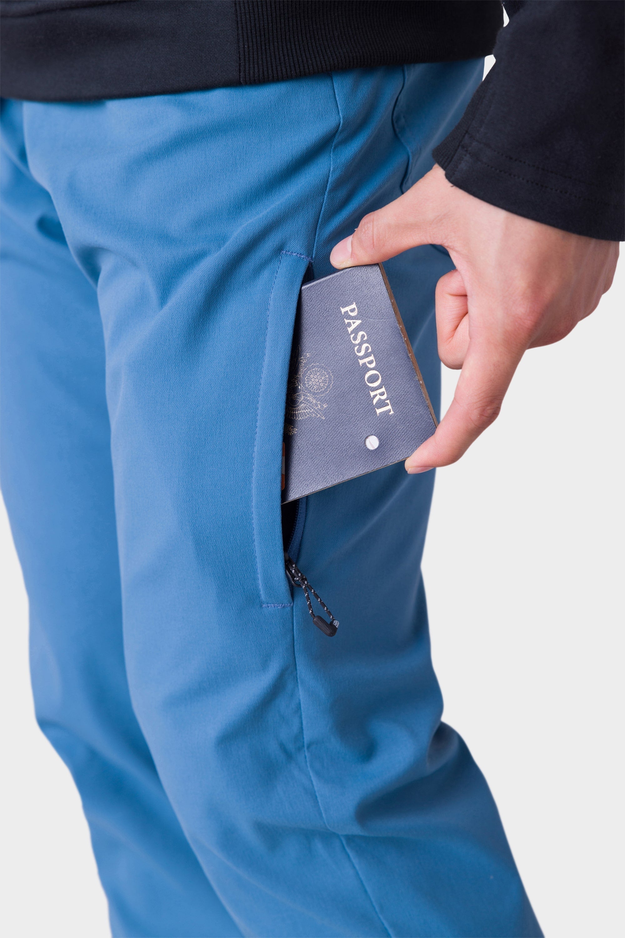 Wearing the 686 Mens Everywhere Merino-Lined Pant - Slim Fit, a person stores their passport in the zippered side pocket, ensuring it stays warm and dry even in cold conditions.