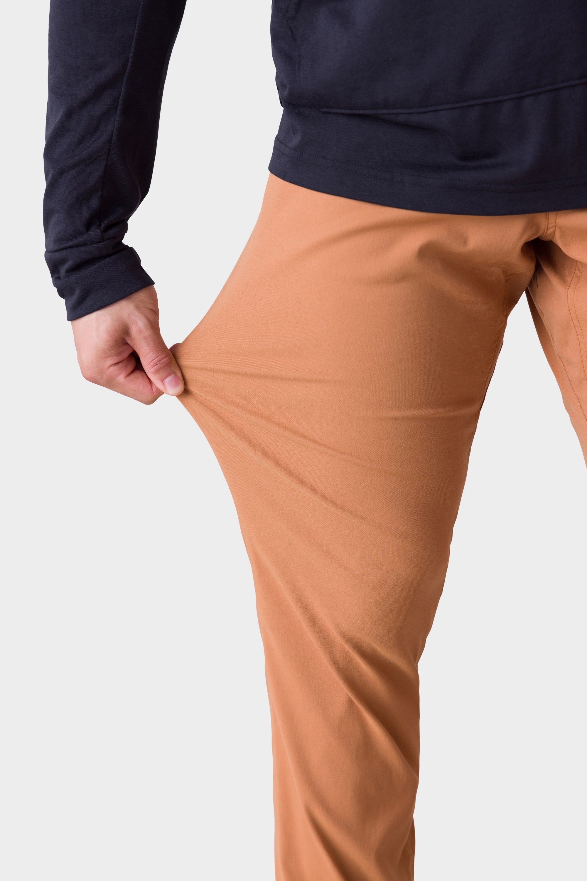 A person wearing the 686 Mens Everywhere Merino-Lined Pant - Slim Fit stretches the fabric to showcase its flexibility, highlighting why these 686 pants are perfect for warmth and comfort in cold weather.
