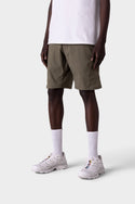 A person wears 686 Mens Anything Hybrid Cargo Short in olive green, paired with a white t-shirt, white crew socks, and white sneakers. Only the lower half is visible against a plain light gray background, emphasizing the minimalist style.