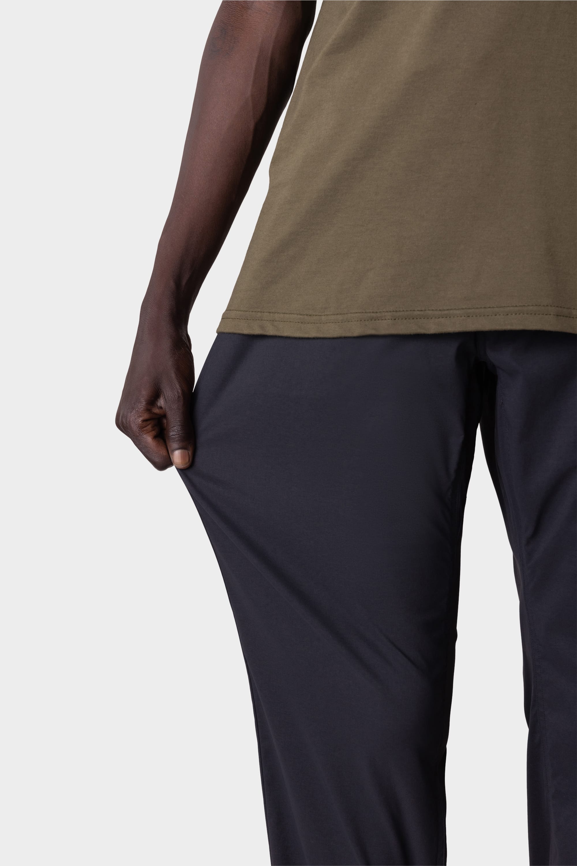 A person in a green shirt stretches the fabric of their 686 Mens Everywhere Featherlight Chino Pant - Relaxed Fit, showing the flexibility and stretchiness of these 686 pants.
