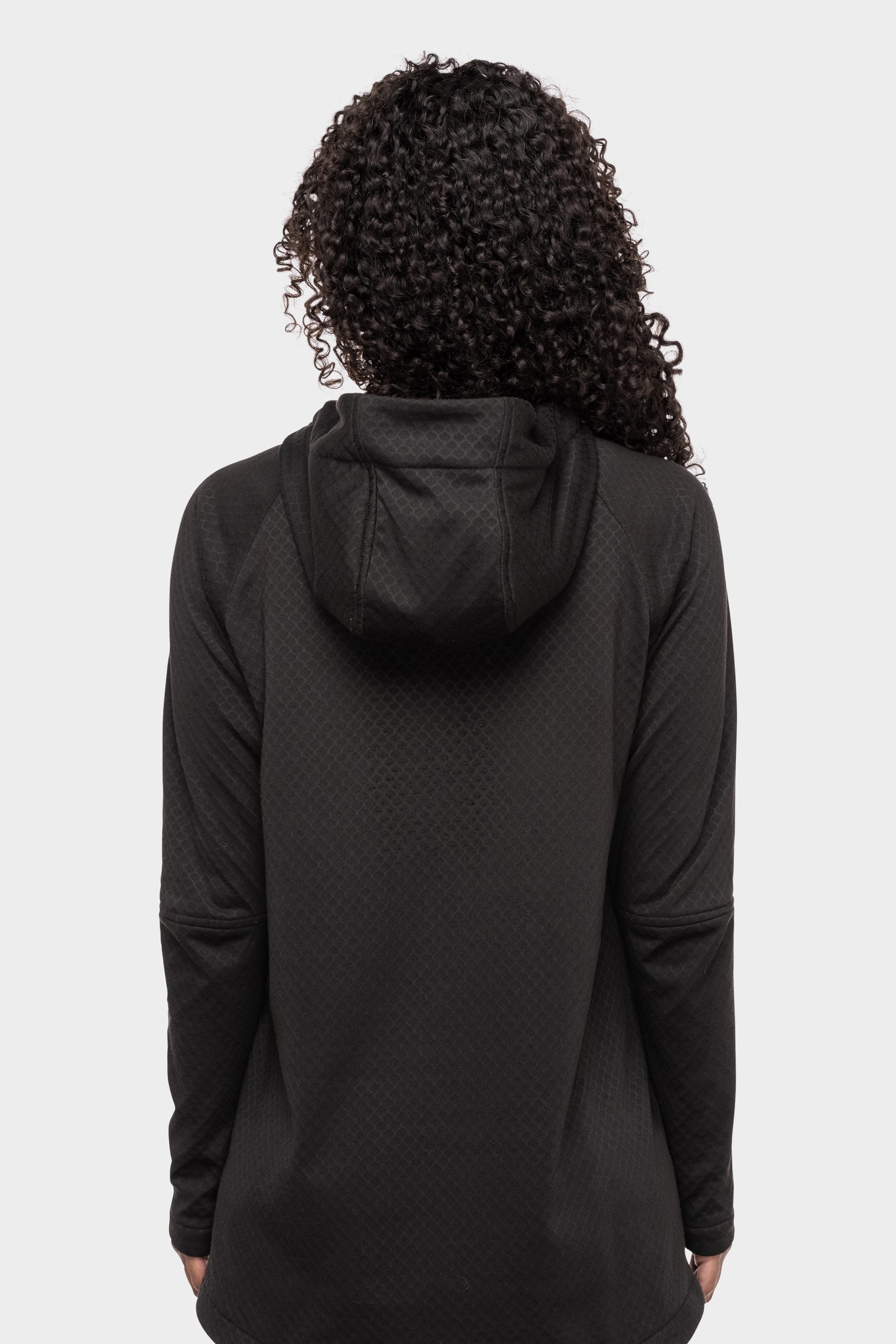 A woman with curly hair is shown from the back wearing the 686 Womens Mission Grid Fleece Hoody by 686, black in color, against a plain white background.