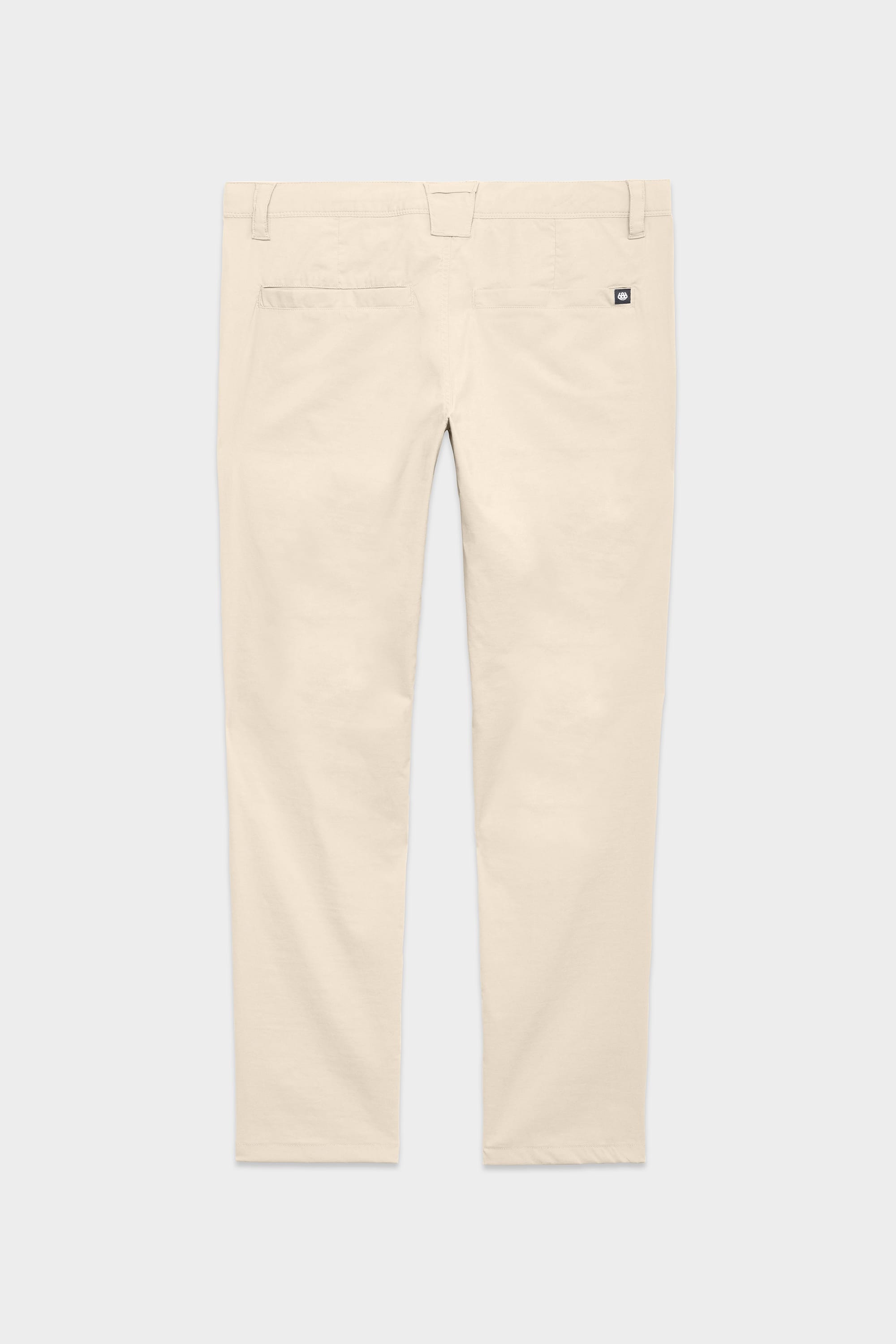 Back view of the 686 Mens Everywhere Featherlight Chino Pant - Slim Fit in light beige, with belt loops, two back pockets, and a black-and-white tag above the right pocket. Ideal for summer or warm-weather outings. Shown on a plain light grey background.