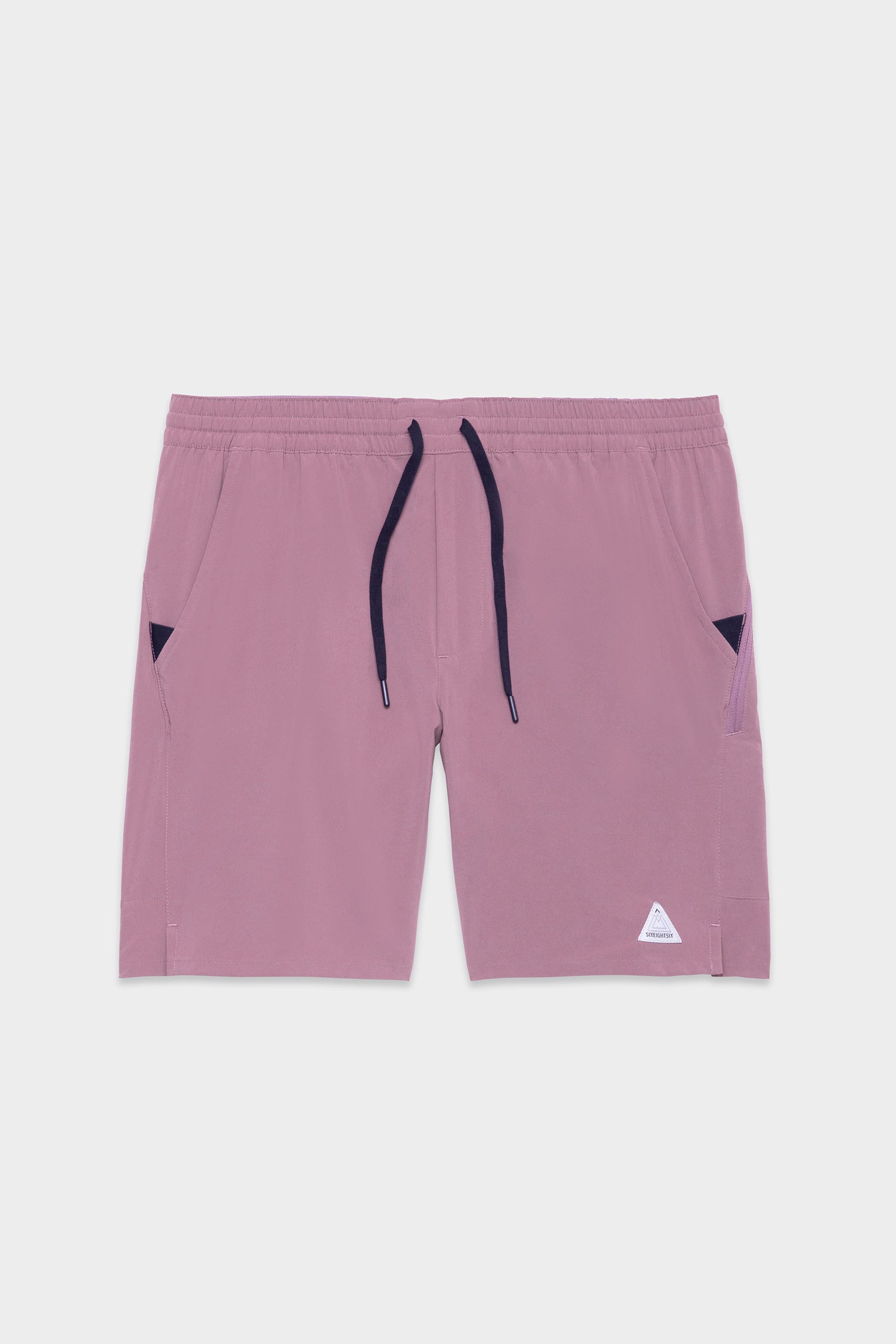 The 686 Mens ATP Stretch Performance Short by 686 features a light pink color, elastic waistband with black drawstrings, side pockets with black lining, and a small white triangular logo on the lower left leg, shown against a plain white background.