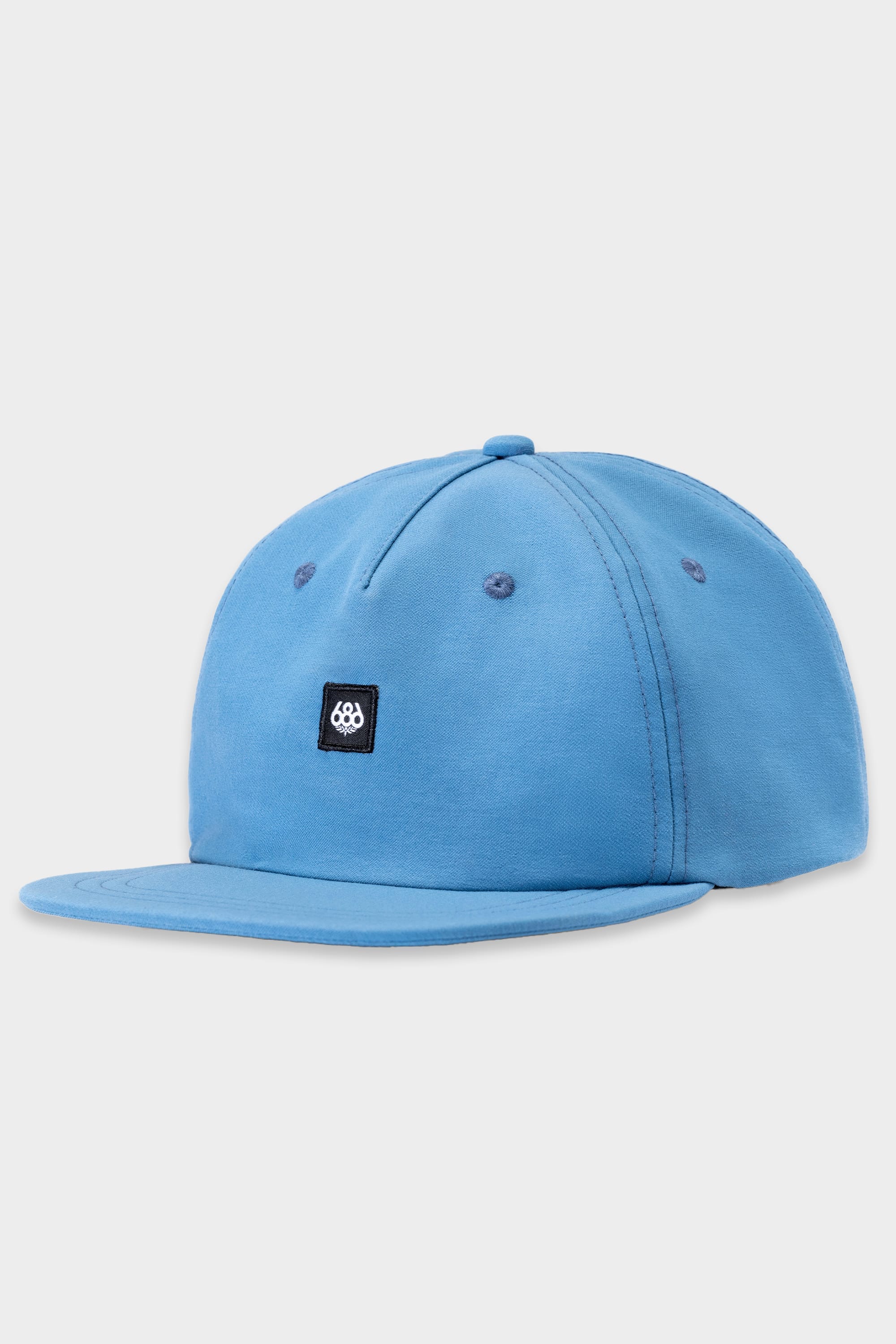 The 686 Packable Everywhere Hat by 686 is a light blue baseball cap with a flat brim, featuring a small black square patch and white geometric logo on the front. Shown against a plain white background.
