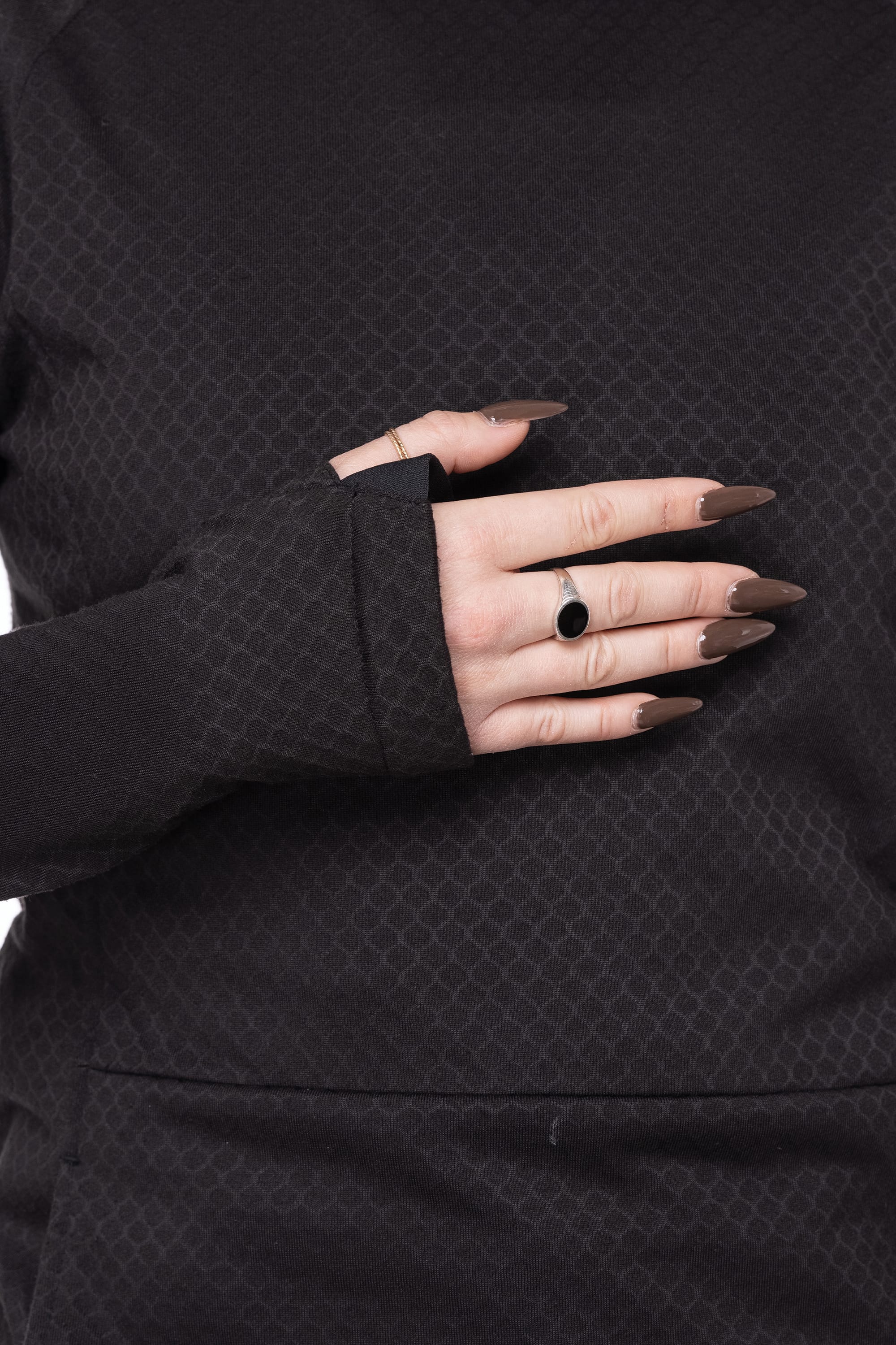 A person wearing the 686 Womens Mission Grid Fleece Hoody with thumb holes rests their hand on their chest, showing off long brown manicured nails and a black stone ring.