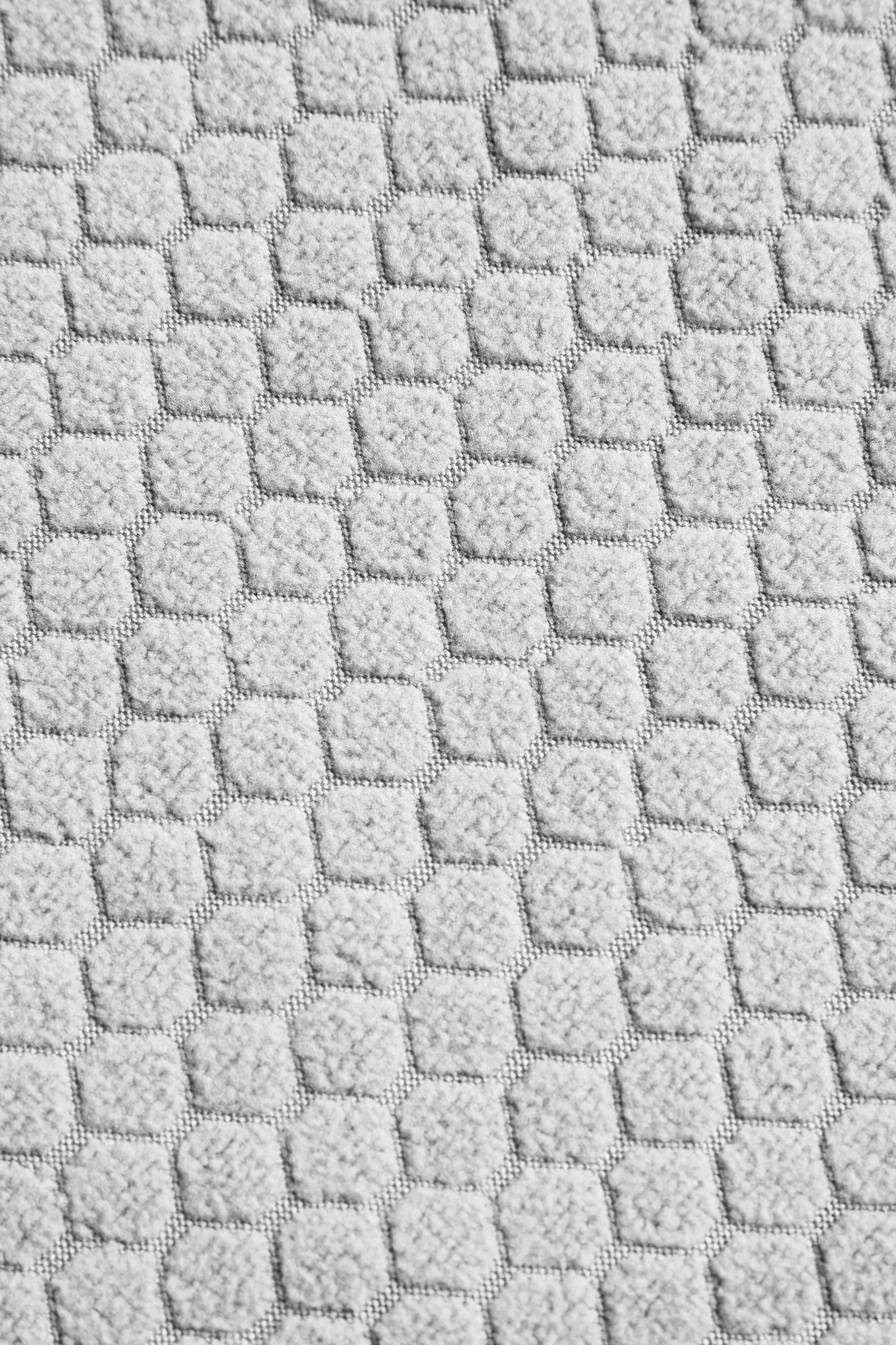 Close-up of the 686 Womens Mission Grid Fleece Hoody by 686 shows its light grey textured fabric, featuring a repeating pattern of raised hexagons and squares.