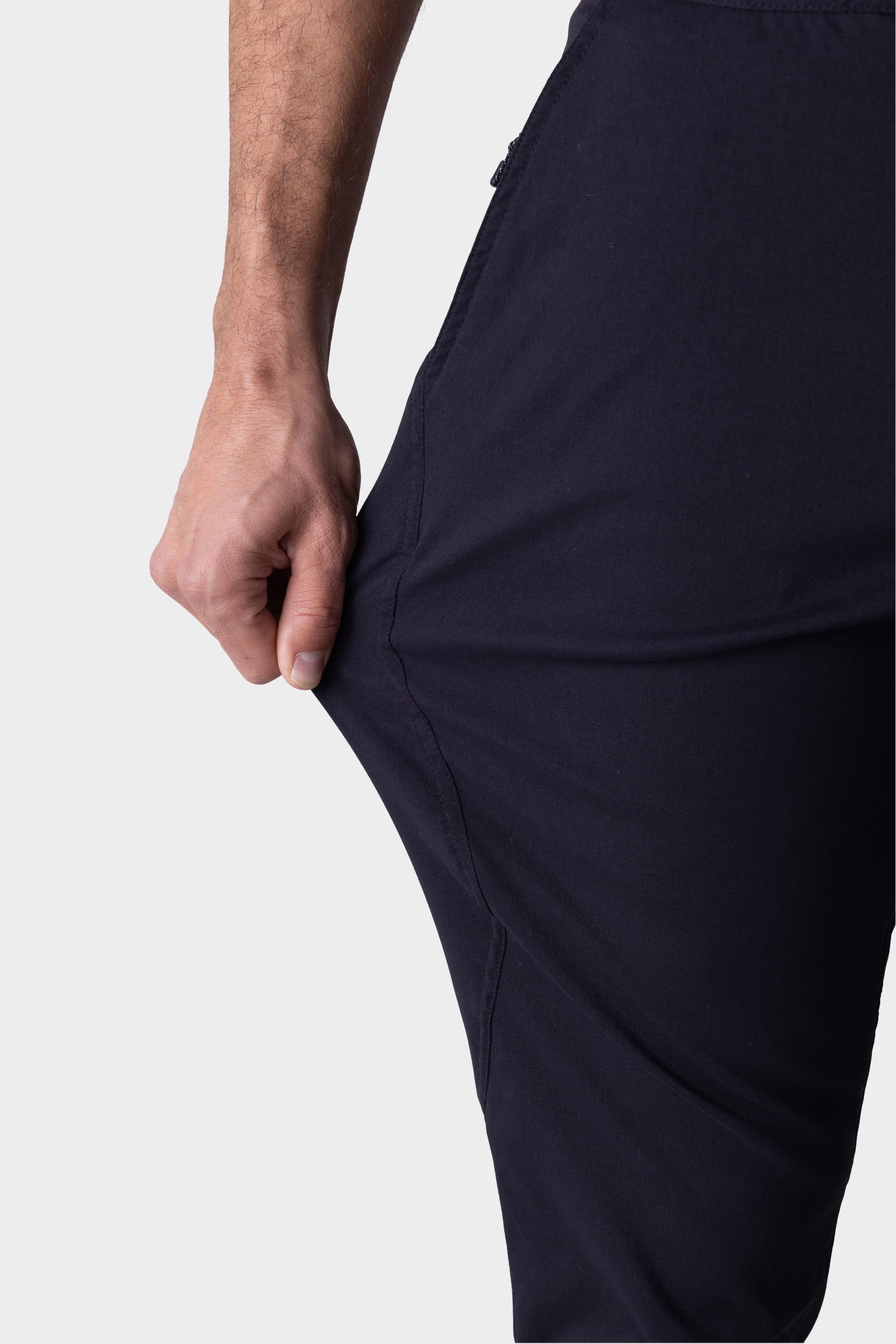 A person stretches the fabric of their 686 Mens Platform Bike Pant - Slim Fit, showing its flexibility, with only their hand, arm, and upper leg visible against a plain background.