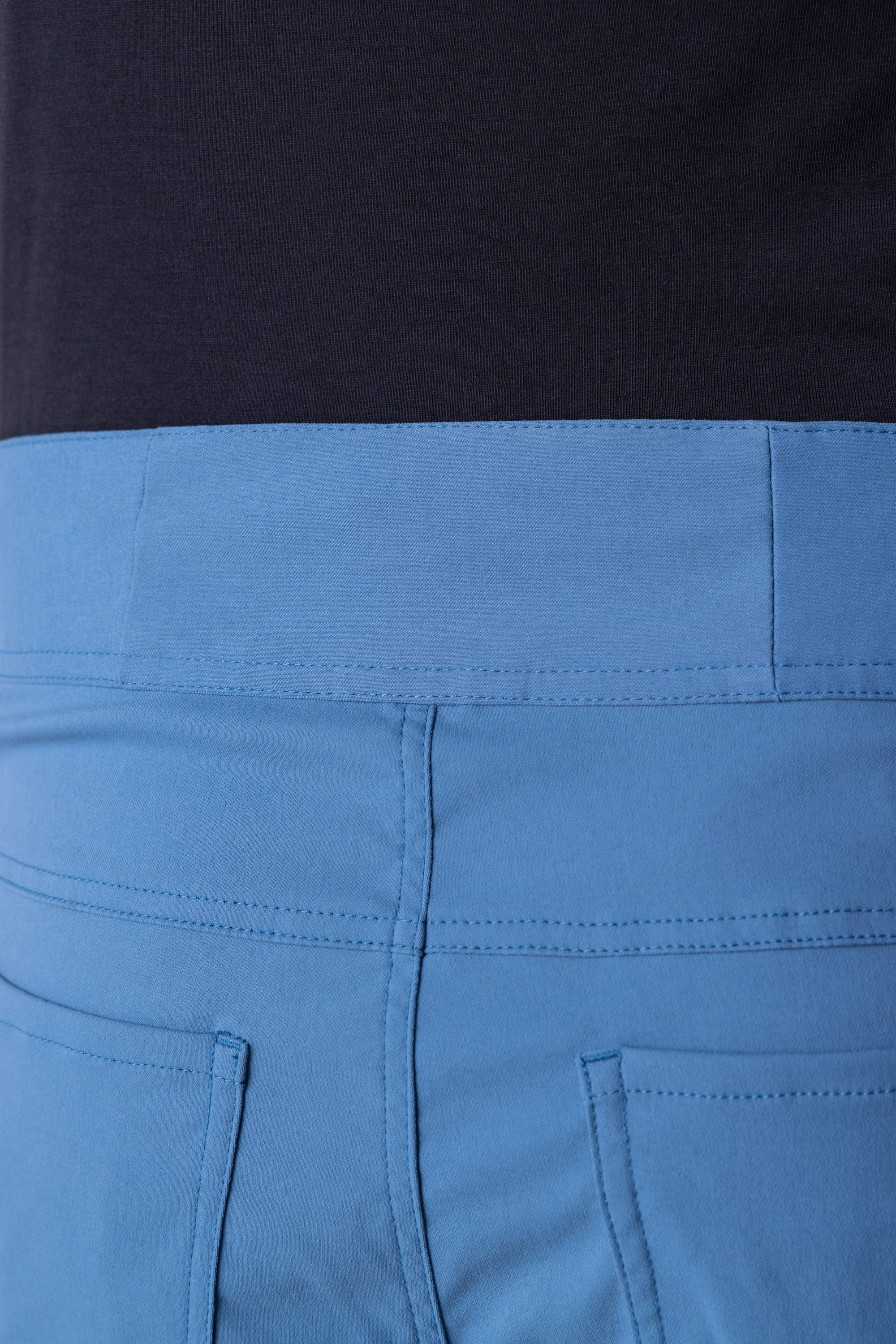 Close-up of the waistband and upper back of the 686 Mens Platform Bike Pant - Slim Fit in light blue, featuring visible stitching and paired with a dark-colored top.